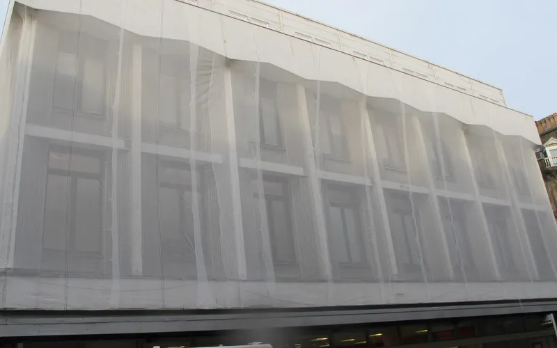 Building facade protected with fine mesh netting during height works