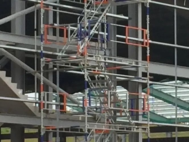 Multi-storey scaffolding stair tower erected against a steel-frame building