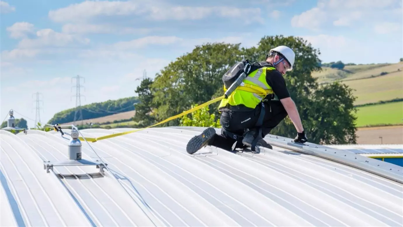 Worker using a Constant Force post lifeline on a curved metal roof