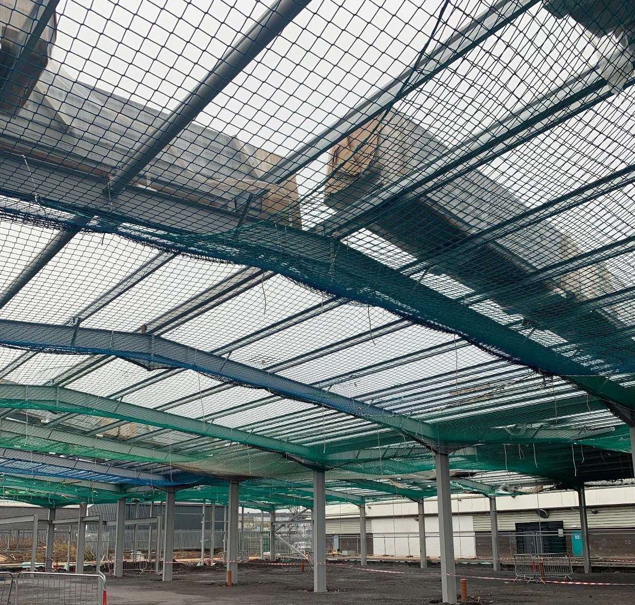 Green safety netting spanning a steel-frame warehouse under construction