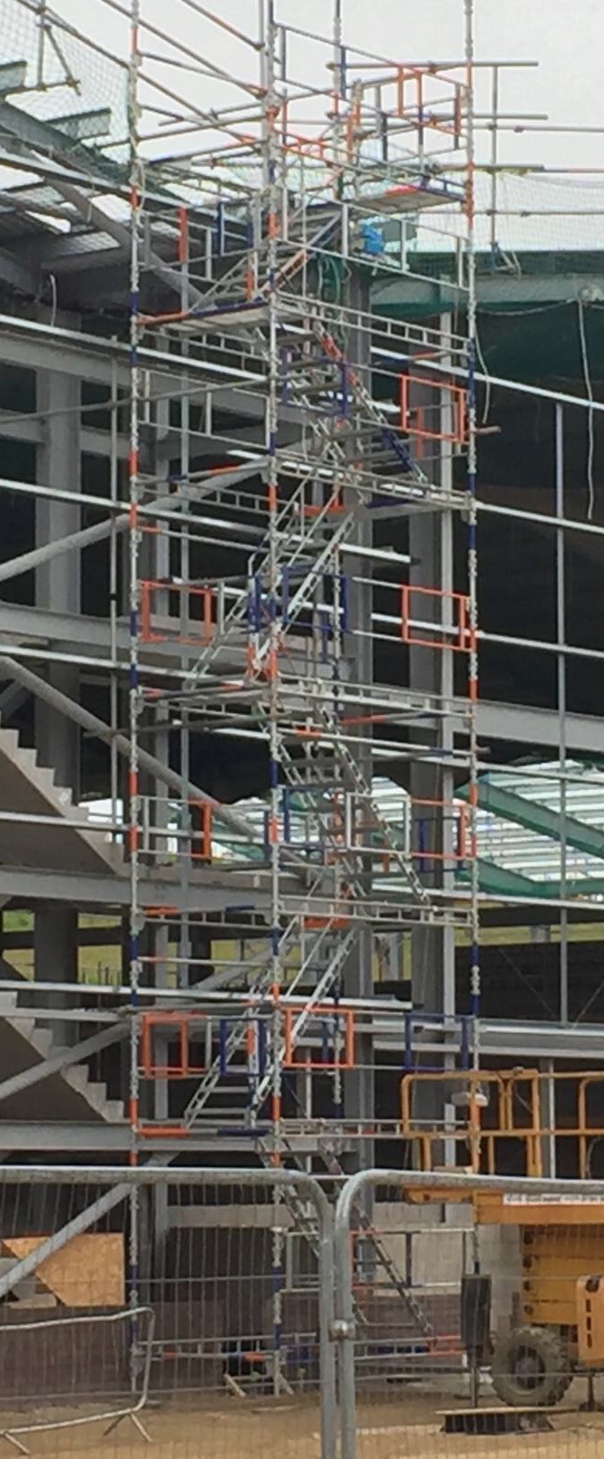 Multi-storey scaffolding stair tower erected against a steel-frame building