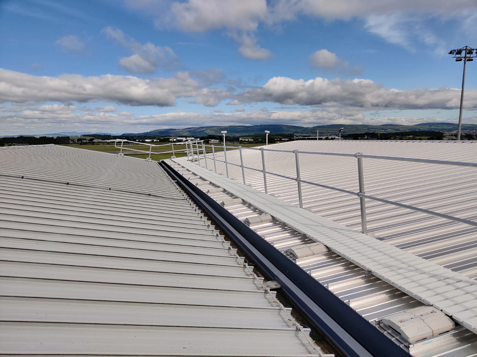 Rooftop walkway with adjacent guardrail providing a protected access route