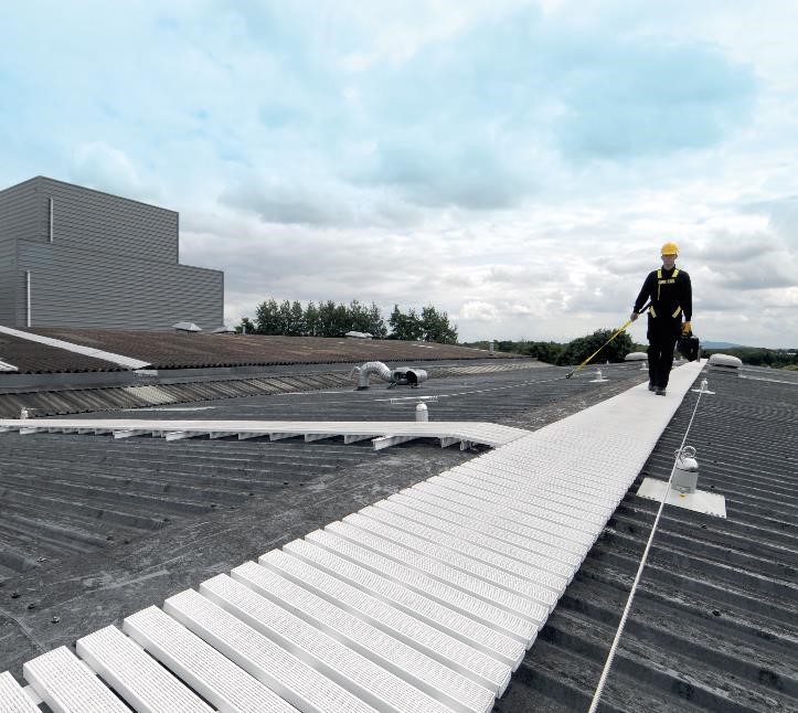White anti-slip rooftop walkway with a worker clipped to an adjacent lifeline